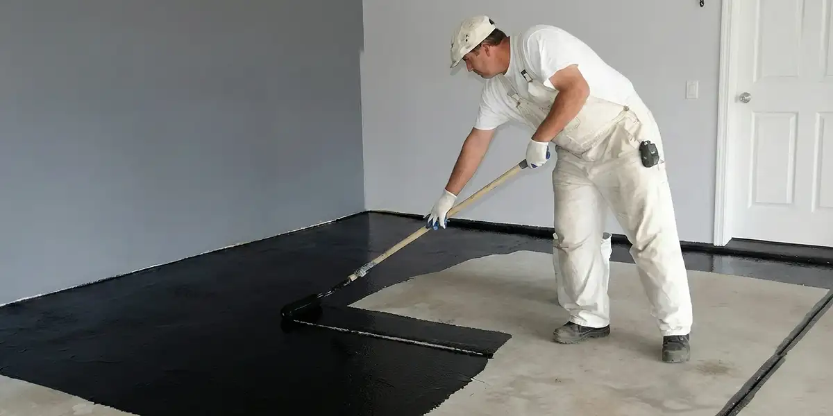 basement waterproofing professional applying waterproof coating to protect a basement floor in Baltimore, MD